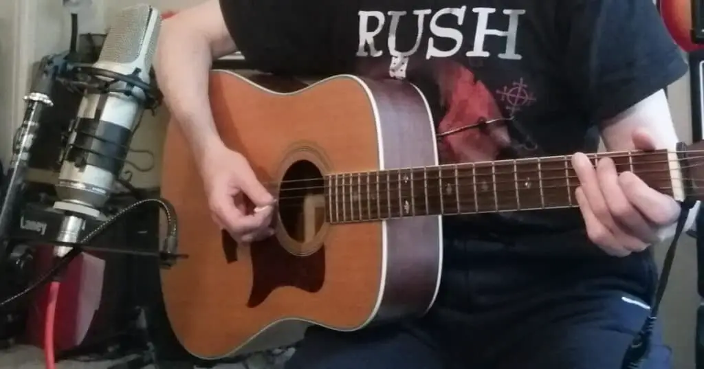 Photo of a microphone recording an acoustic guitar placed above the strings, angling down