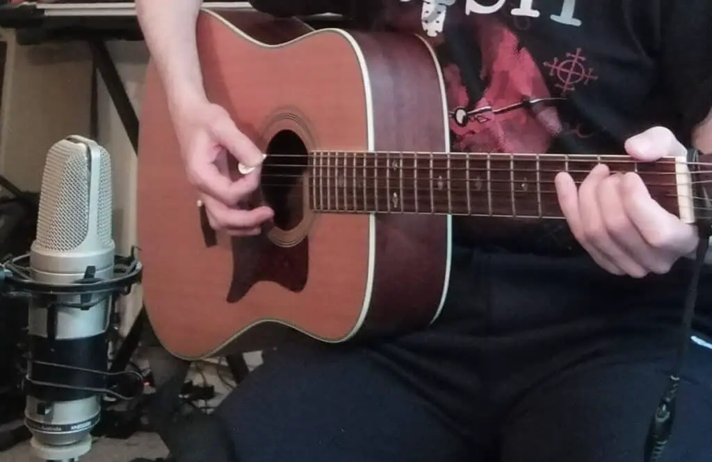 Photo of a microphone recording an acoustic guitar placed in front of the 12th fret