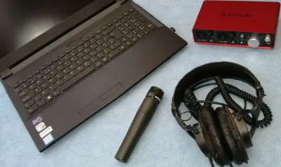 Photo of a laptop, microphone, headphones and audio interface