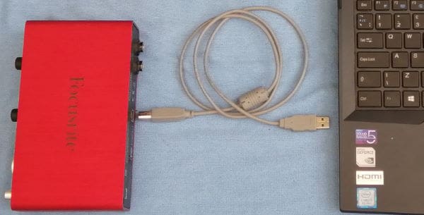 Photo of an audio interface, its USB connecting cable and a laptop