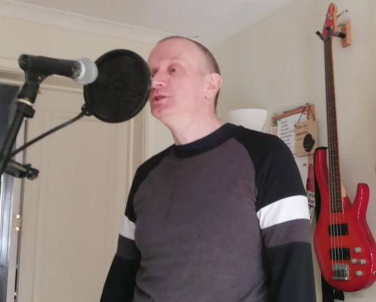 Photo of a singer recording vocals in a home studio