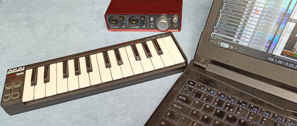 Photo of a small musical keyboard, an audio interface and a laptop running digital audio workstation (DAW) software